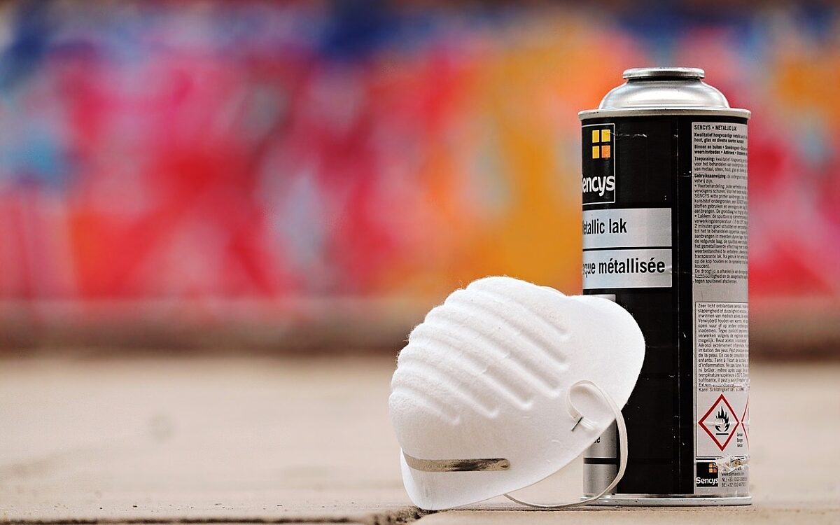 Eine Spraydose und eine Maske vor einer Graffiti-Wand Eine Spraydose und eine Maske vor einer Graffiti-Wand